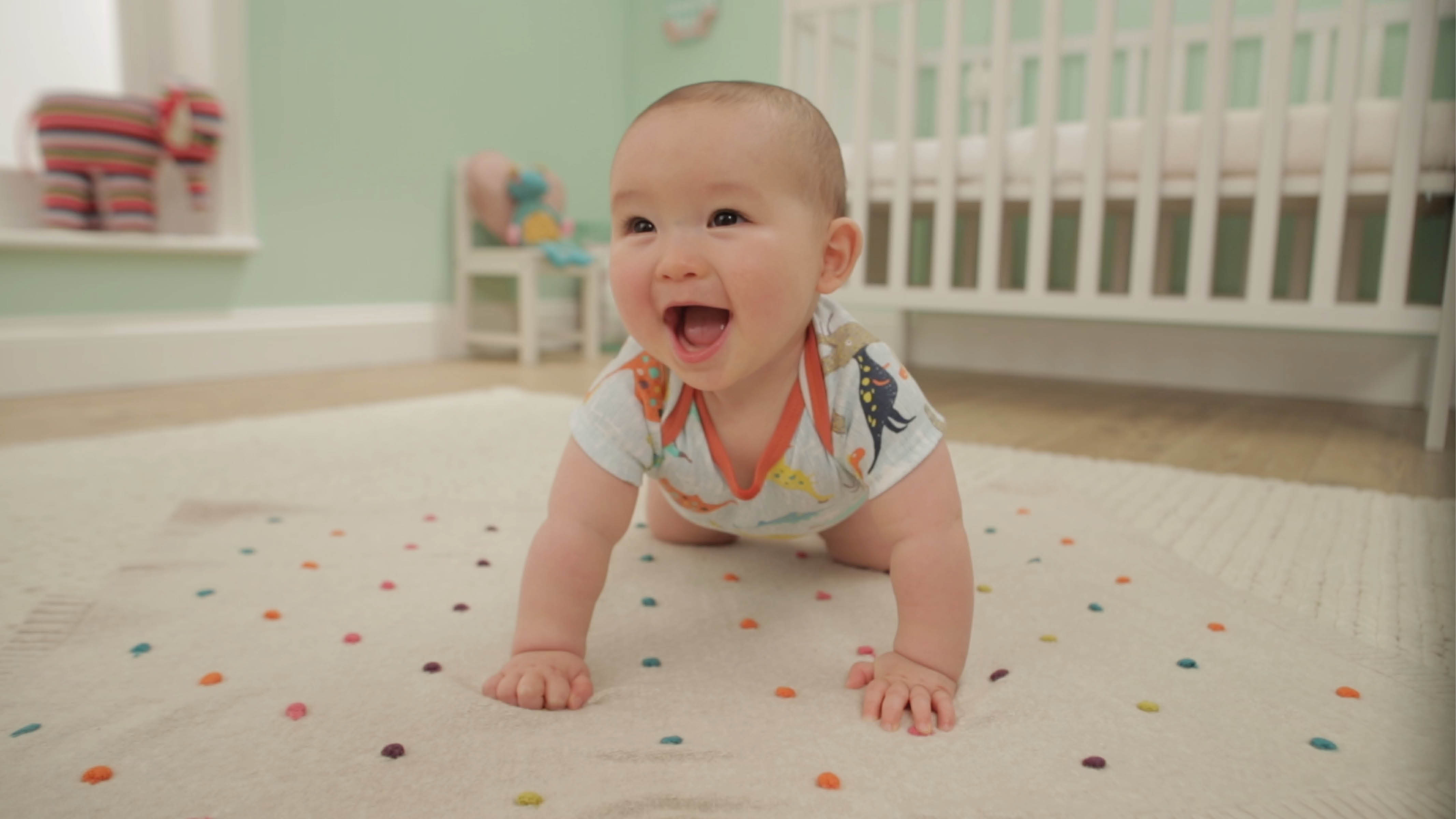 Happy baby in nursery Choose a comfortable, stain-resistant rug that complements the colour on your walls, and stock up on some soft floor pillows.